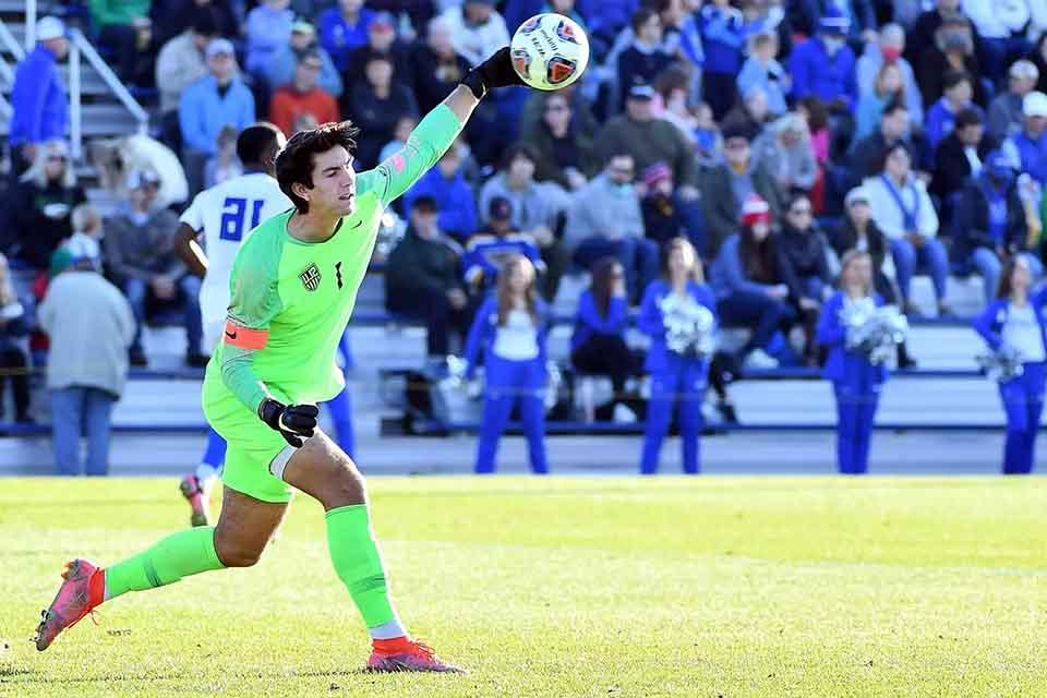 A soccer player throws a ball down onto the field.